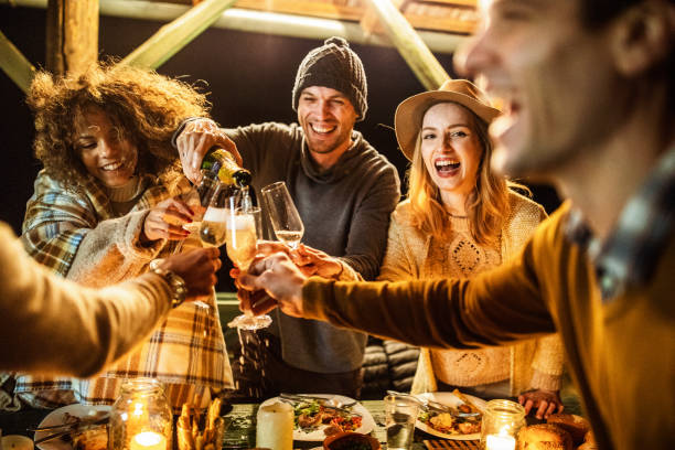 istock Cheerful friends pouring champagne on a dinner party by night. 1159591907