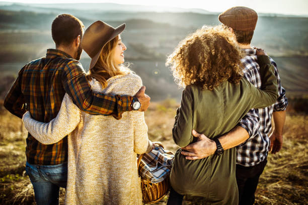 istock Back view of two couples going on a picnic in a meadow. 1159592096