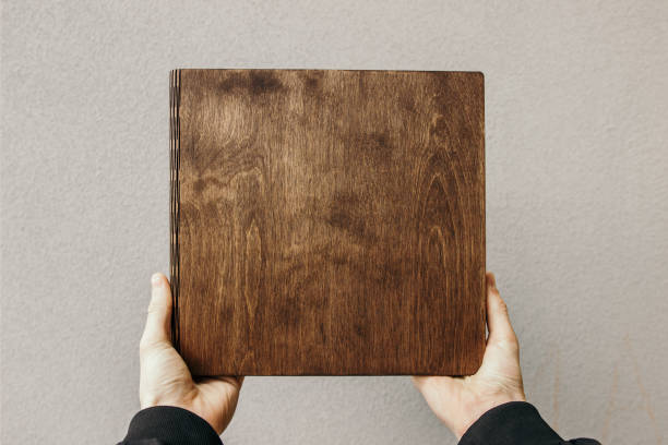 man holds photobook in a wooden cover. guy holds notebook with plywood cover - book photo album publication open imagens e fotografias de stock