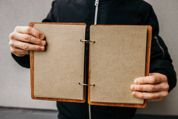 istock Closeup of guy holding blank open book. Education concept. guy holds open empty notebook. two hands. craft page 1159594609