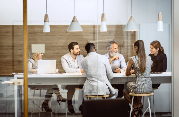 istock Business People Sitting Around The Desk, Discussing 1159595165