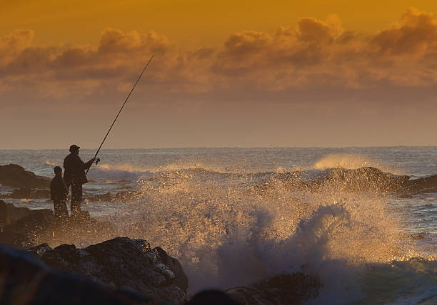 Fisherman at sunrise Father and son fishing at sunrise. sea fishing stock pictures, royalty-free photos & images