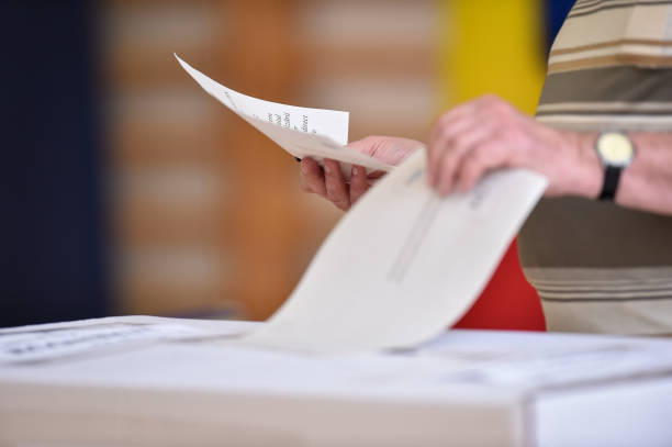 Hand of a person casting a vote into the ballot box during elections stock photo