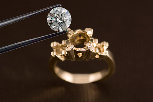 A diamond being examined before being set into an engagement ring OR a diamond being removed from an engagement ring.