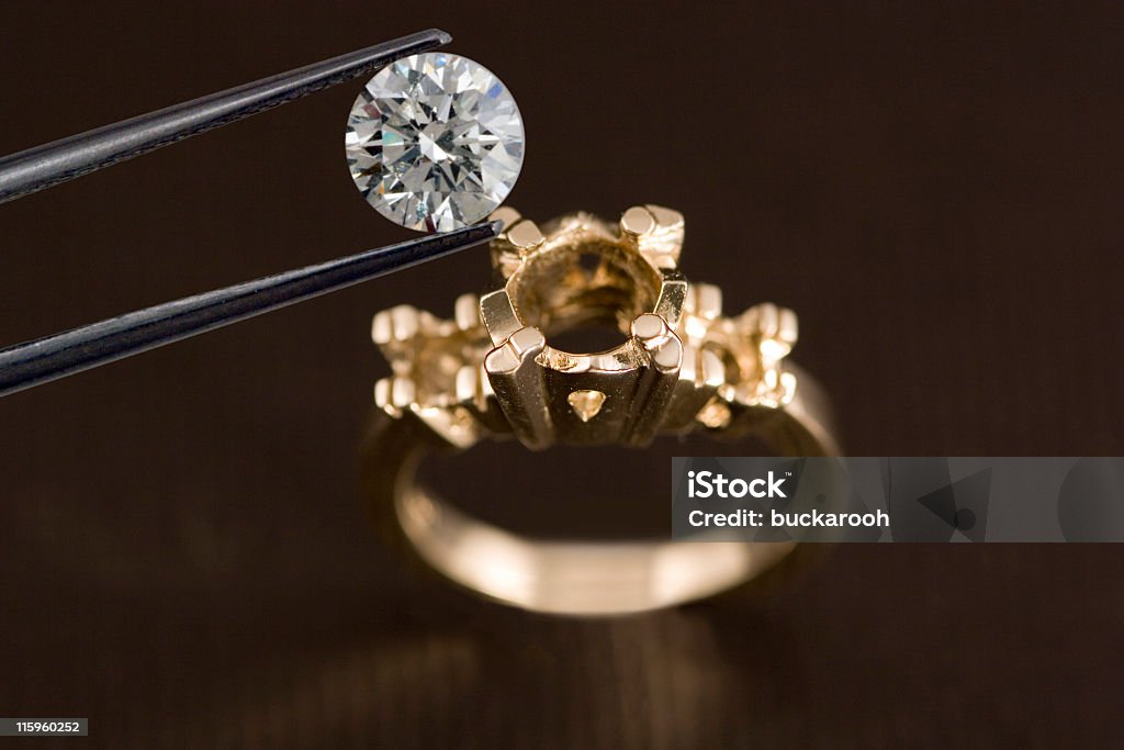 Photo of a Diamond Above an Engagement Ring A diamond being examined before being set into an engagement ring OR a diamond being removed from an engagement ring. Arranging Stock Photo