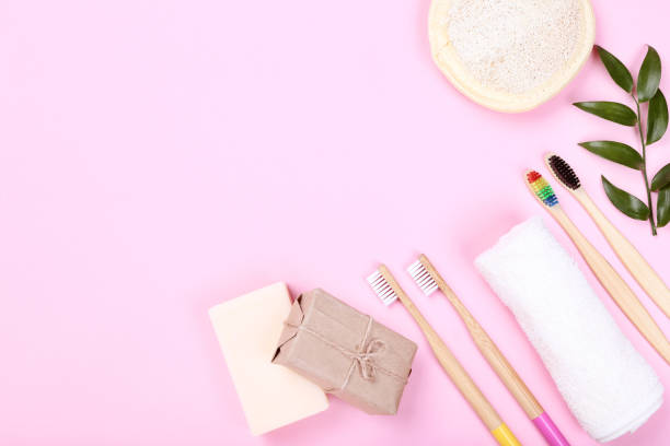 istock Bamboo toothbrushes with towel, washcloth and soap on pink background 1159605032