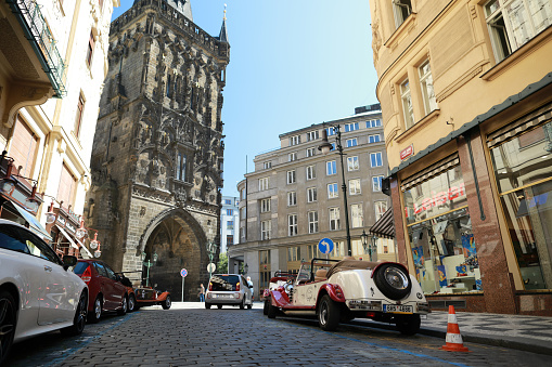 Prague, Czech Republic - June 27, 2019: View of Landmark architecture building call name Powder tower(Prasna brand) in the centre city with old retro car for excursion  tour in sunny day on blue sky background.