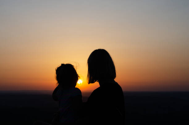 istock Mom and  daughter relaxing  at sunset. 1159608089