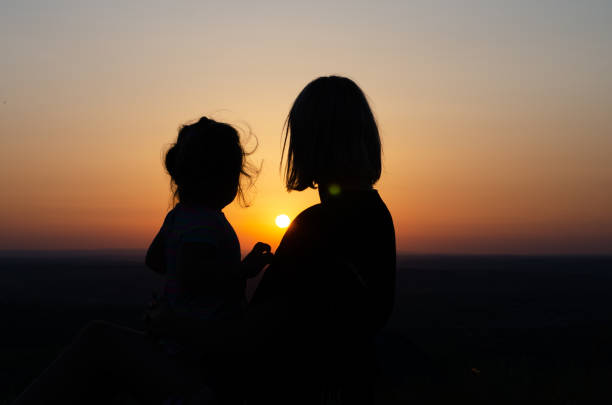 istock Mother and daughter who sit and look at the sunset . 1159608097