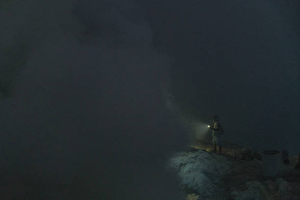 istock Man with flashlight in  Ijen volcano and sulphur minings 1159609455