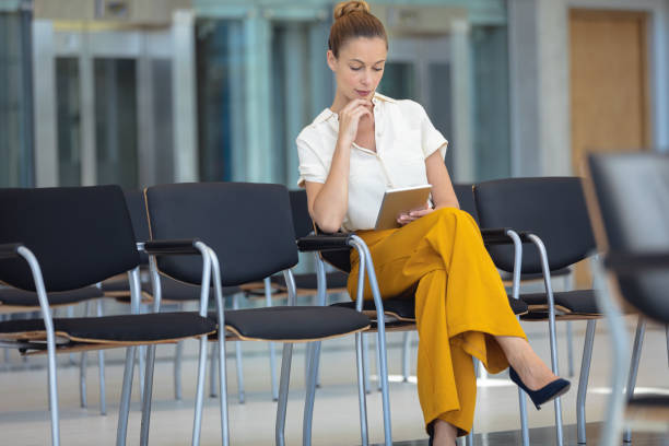 istock Young Caucasian female executive looking at digital tablet while sitting on chair in empty conferenc 1159609808