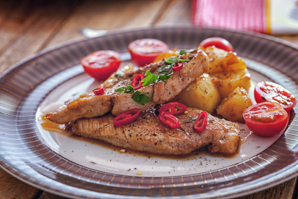 Grilled pork chops with potatoes in sweet honey mustard sauce, close-up, no people