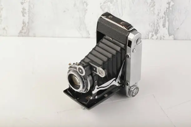 Old medium format rangefinder film camera on white cement background.