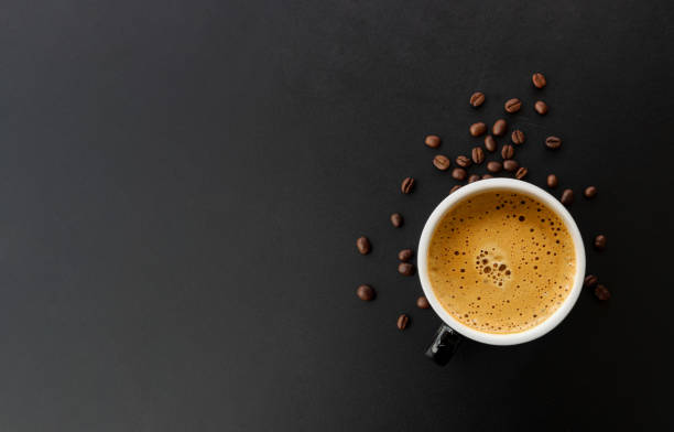 istock hot espresso and coffee bean on black table with soft-focus and over light in the background. top view 1159612491