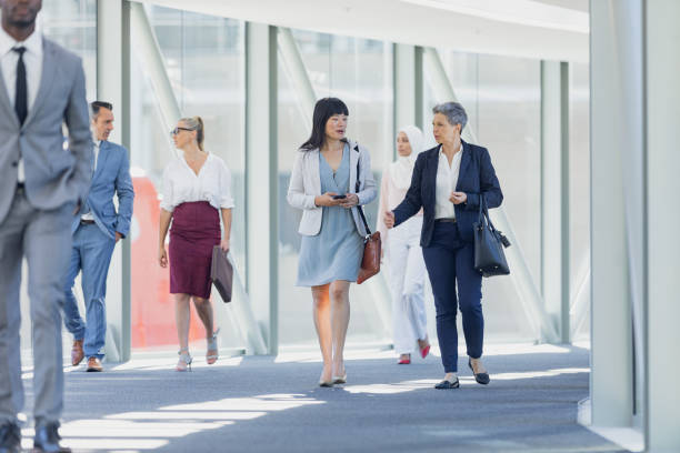 istock Diverse businesswomen interacting with each other while walking in corridor 1159613927