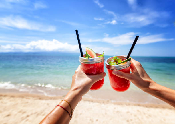 Fresh watermelon juice in two glasses against a bright tropical landscape, background of the sea. stock photo
