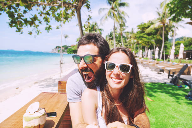 Young happy couple on honeymoon vacation have fun beach background in cafe. Build funny faces Young happy couple on honeymoon vacation amuse on tropical beach background in cafe. Build funny faces arabian sunglasses stock pictures, royalty-free photos & images