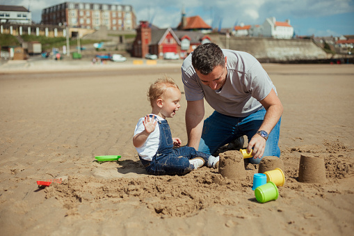 Father and son building sandcastles at the beach in summer.