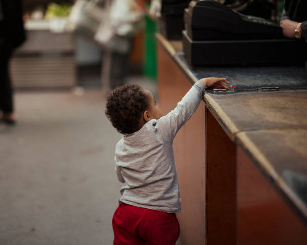 Peeking Over The Counter Young boy reaching up to put a debit card on a counter. kid peaking over counter stock pictures, royalty-free photos & images