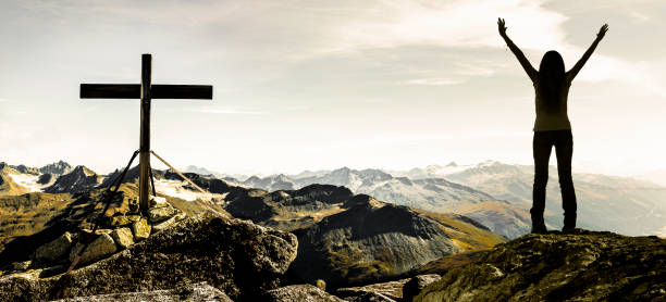 happy woman at summit cross in swiss alps