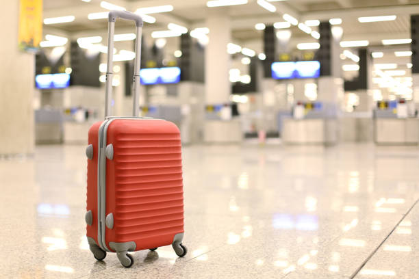 Closeup shot of bellboy carrying luggage in hotel hallway, focus on blue suitcase on floor by room door