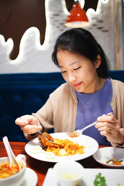 istock Asian woman is eating spicy fired rice in restaurant. 1159619990