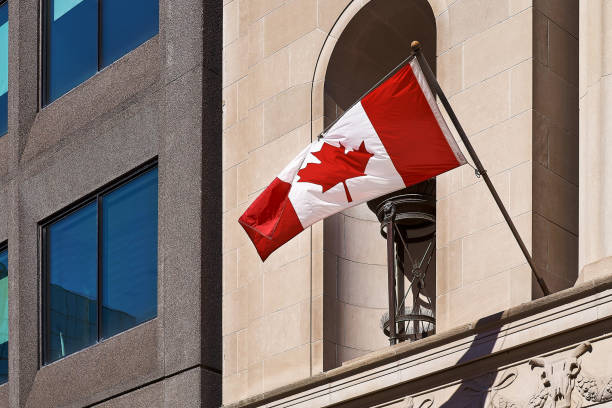 Big Canada flag waving in the wind with a wall in the background