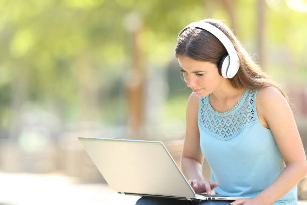 istock Serious woman using a laptop and headphones in a park 1159620199
