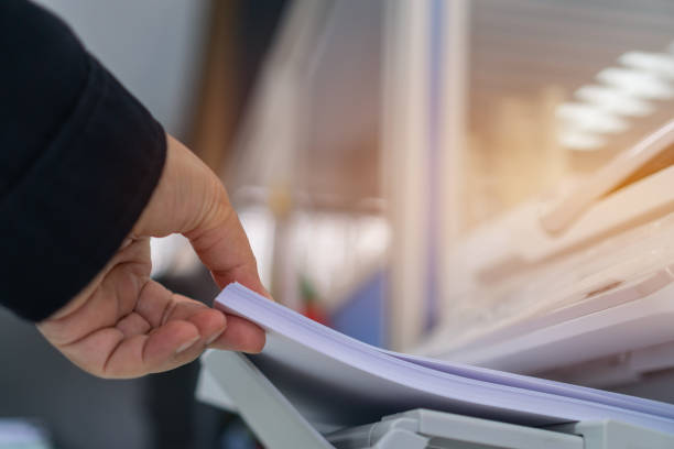 istock Business printer / printing documents in office concept: Businessman press white paper in laser printed cartridge feeder, scanner machine for copy document to report in busy modern offices background 1159622832