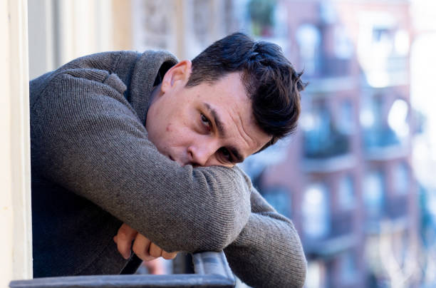 istock Sad unhappy depressed young man crying and suicidal feeling desperate, isolated and worthless staring down the street on home balcony In People Depression and Mental Health concept. Urban background. 1159627072