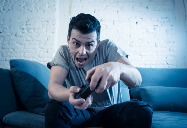 istock Portrait of young student man spending time playing video games using wireless remote joystick with freak intense happy face having fun in Male game addiction to console play station and video. 1159627075
