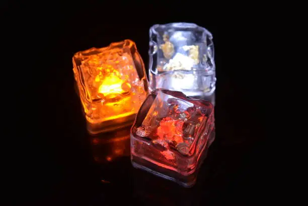 Photo of Beautiful plastic ice cubes with bright diode light. Red, yellow, white lighting for parties, recreation creative imagination.