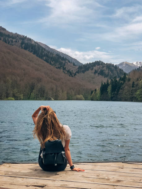 istock Young woman sitting on lake dock 1159627636