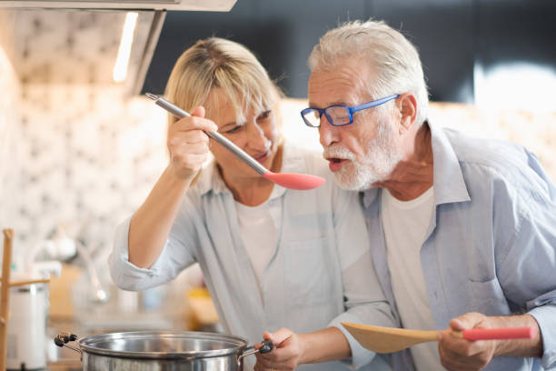 closed up senior caucasian couple are cooking and testing a meal or health food which smile and felling happy in kitchen at home. old woman let a man test food. senior family activity at home concept. - cooking senior adult healthy lifestyle couple imagens e fotografias de stock