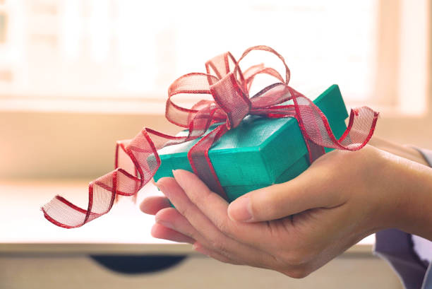 istock Woman give green gift box with background warm light from window. 1159627860