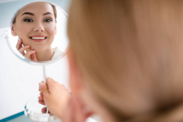 istock Round cosmetic mirror with reflection of smiling lady 1159632114