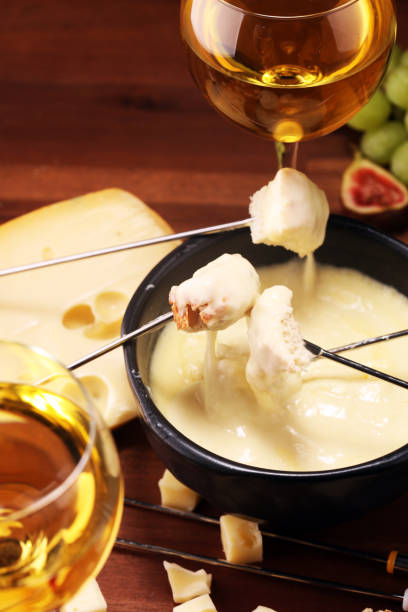 istock Gourmet Swiss fondue dinner on a winter evening with assorted cheeses on a board alongside a heated pot of cheese fondue 1159632449