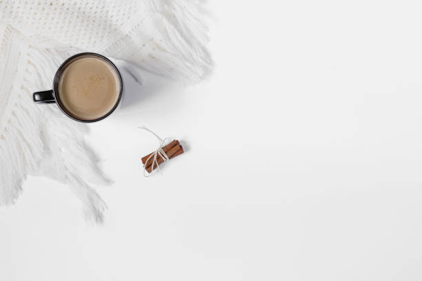 istock Black cup of white coffee with cinnamon and white crocheted scarf 1159633743
