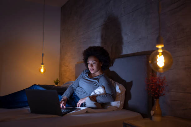 istock Woman lying in bed surfing the net on a laptop computer 1159634037