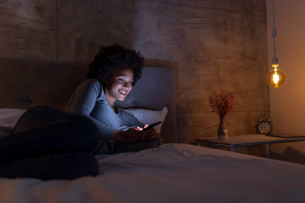 istock Woman lying in bed typing a text message 1159634298
