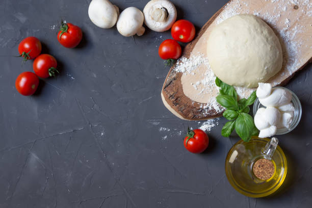 istock Pizza ingredients on the grey background with copy space, dough, tomatoes, mushrooms, basil, mozzarella, olive oil 1159635733