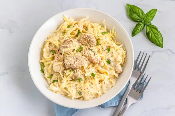 One Pot Chicken Alfredo Pasta in a Bowl Garnished with Basil Leaves Directly from Above Photo.