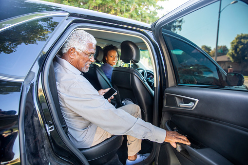A senior black man gets into the car that has arrived for him.