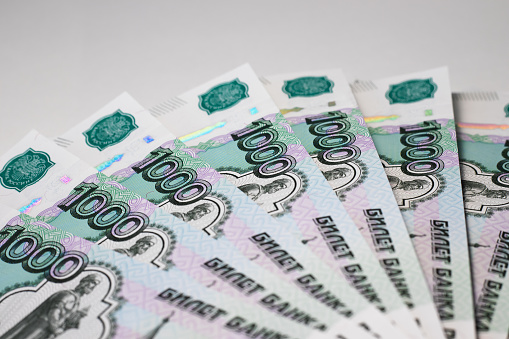 Russian banknotes in denominations of one thousand rubles are on a table in the lower right corner in a semicircle. White background.