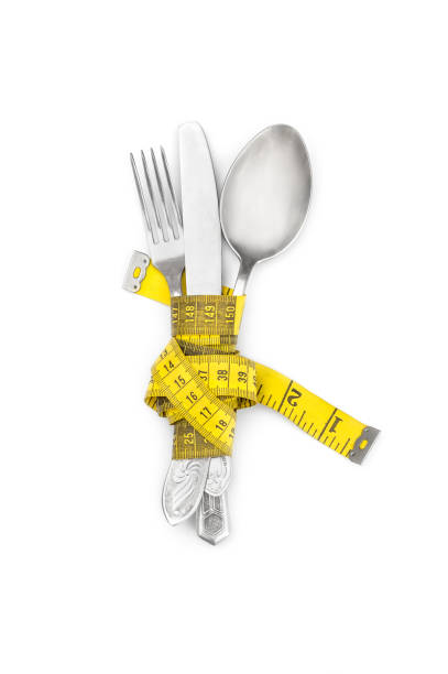 Fork, spoon and knife wrapped by measuring tape on white. Top view.
