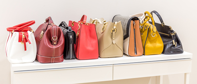 Collection of handbags standing in a row on a white table