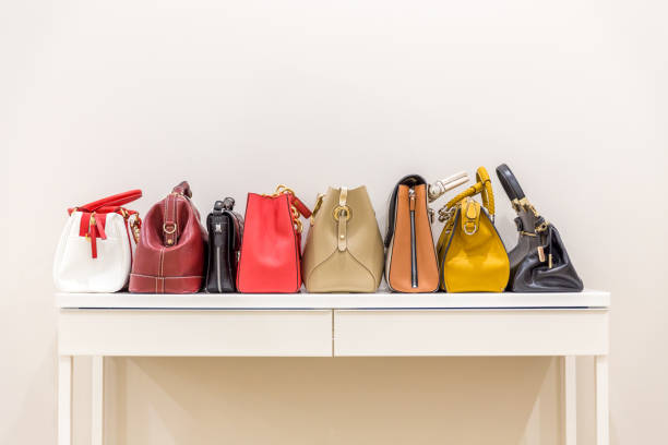 Collection of handbags standing in a row on a white table