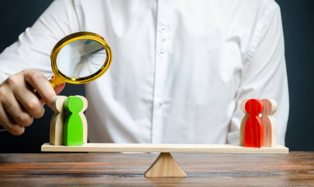 istock A man with a magnifying glass is looking at the rival red and green figures groups on scales. conflict resolution and the search for a compromise in the dispute. Research argument of each side 1159643300
