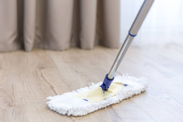 istock Cleaning floor with white mop near sofa 1159643573
