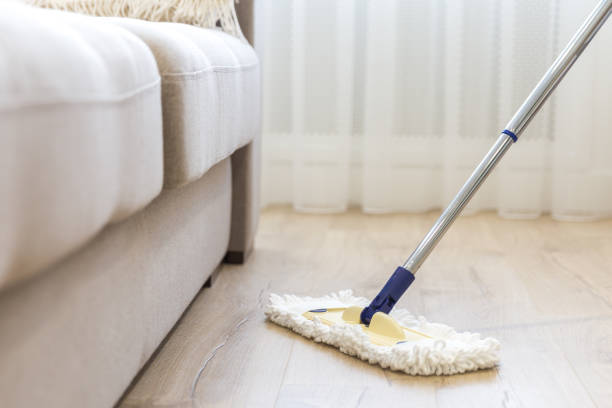 istock Cleaning floor with white mop near sofa 1159643613